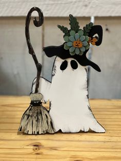 a white and black snowman with a flower on his head next to a broom