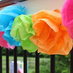 tissue paper flowers are hanging on the fence