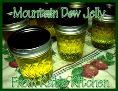 four jars filled with yellow liquid sitting on top of a tablecloth covered table cloth