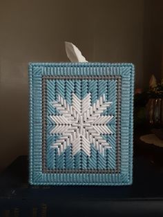 a tissue dispenser sitting on top of a blue bookcase next to a candle