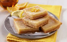 lemon squares on a plate next to a cup of tea