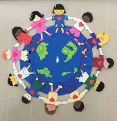 a group of children standing around a blue and green globe with paper cutouts on it