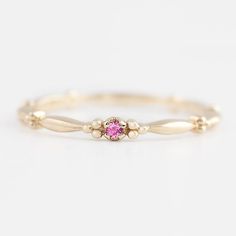 a rose gold ring with a diamond in the center and two small beads on each side