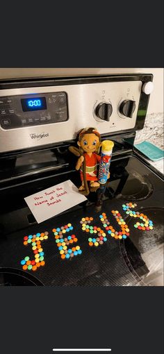 a toy monkey sitting on top of a stove next to some candy and a sign