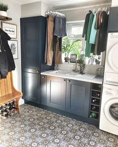 a washer and dryer in a small room with blue cabinets, tile floor