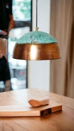 a wooden table topped with a metal light and a cutting board on top of it