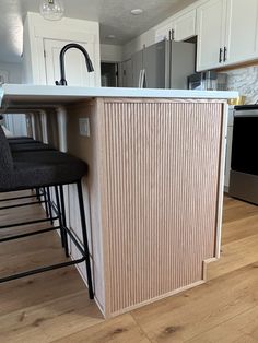 a kitchen with an island and bar stools next to the counter top in front of it