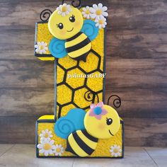 a cake shaped like the number one with a bee and flower on it's side