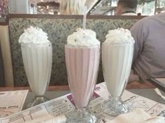 three milkshakes sitting on top of a table next to each other