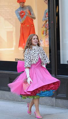 a woman in a pink dress and leopard print jacket is walking down the street with her handbag