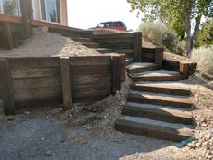 a car parked on the side of a road next to wooden steps and gravel area