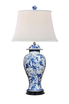 a blue and white vase lamp with a shade on it's base, sitting against a white background