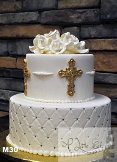 a three tiered cake with white roses on top and a cross on the side