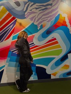 a woman standing in front of a colorful wall