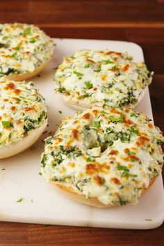 four bagels with cheese and spinach on a white plate