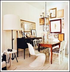 a dining room with white chairs and pictures on the wall