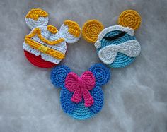 three crocheted mickey and minnie mouses on a white surface with a pink bow