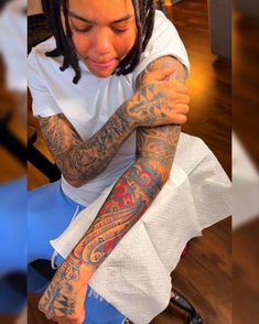 a woman with tattoos on her arm sitting down