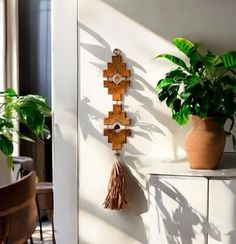 a wooden cross hanging on the wall next to a potted plant