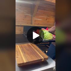 a person cutting up vegetables on top of a wooden board in front of an oven