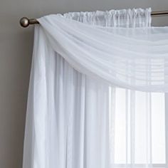 the curtains are hanging in front of the window with white drapes on top of them