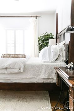 a bed with white sheets and pillows in a bedroom