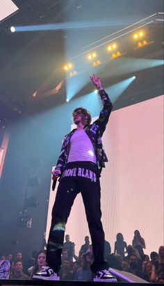 a man standing on top of a stage with his arms in the air