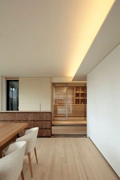 an empty room with white chairs and wooden tables in front of a sauna steam bath