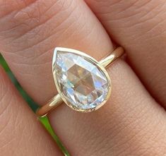 a close up of a person's hand with a gold ring and a white diamond