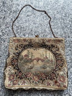 "This is a beautiful vintage French antique circa 1930 Petit pointe brocade evening bag.  The piece appears to be a cotton brocade featuring a river scene surrounded by flowers. The image is the same on both front and back. The inside has a satin lining and a tag that says made in France. The body of the Purse measures 5 1/2\" x 6 1/2\"  The frame measures 6 1/4 inches and it's 2 inches deep The chain measures 13 inches. Overall this item is in very good condition. There  is some wear to the bra Vintage Tapestry Pouch Bag, Vintage Evening Bag In Tapestry Material, Vintage Formal Tapestry Bag, Vintage Tapestry Bag For Formal Occasions, Vintage Tapestry Bag For Evening, Antique Tapestry Evening Bag, Formal Vintage Tapestry Bag, Antique Tapestry Bags For Everyday, Vintage Tapestry Shoulder Bag For Evening