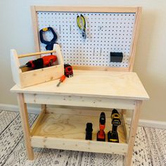 a workbench with tools and pegs on the top, in front of a wall mounted pegboard