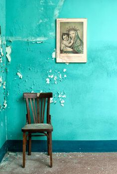 an old chair sits in the corner of a room with peeling paint on the walls