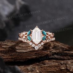 an engagement ring with blue stones and diamonds on top of a tree stump in the woods