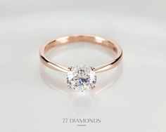 a rose gold ring with an oval cut diamond in the center, on a white background