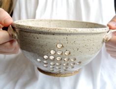 a close up of a person holding a bowl with holes in the bottom and sides