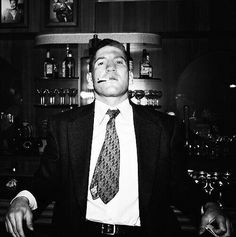 a man wearing a suit and tie standing in front of a bar