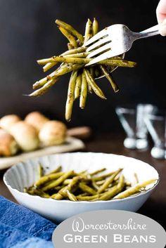 a person holding a fork full of green beans in a white bowl on top of a blue cloth