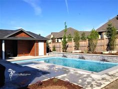 an empty swimming pool in the middle of a residential backyard with wooden fence and trees