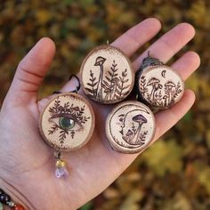 three wooden buttons with designs on them in the palm of someone's left hand