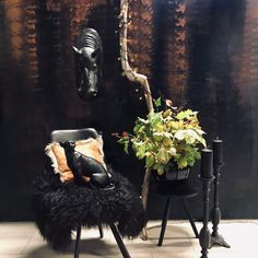 a chair with a plant in it next to a horse head on the wall and a potted plant