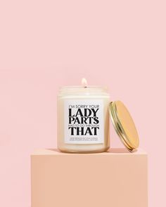 a candle sitting on top of a pink block next to a jar of lip bale