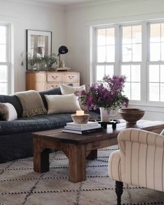 a living room with two couches, a coffee table and flowers in vases