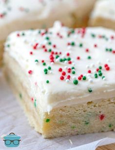 a piece of cake with white frosting and sprinkles on it next to some glasses