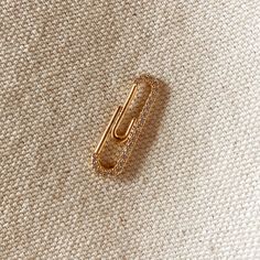 a gold colored hair clip on a white fabric with small crystals in the center and bottom