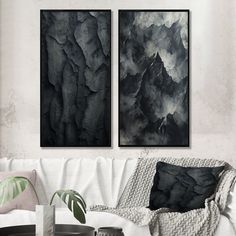 two black and white paintings hanging on the wall above a couch in a living room