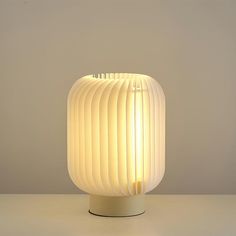 a white lamp sitting on top of a table next to a gray wall and floor