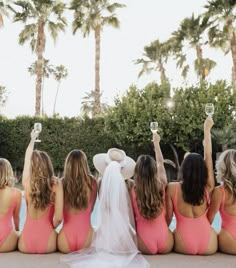 the bridesmaids are sitting by the pool with their hats on