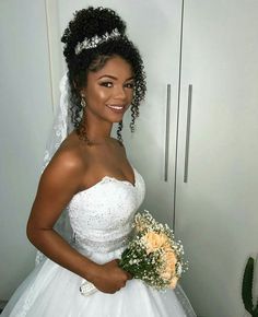 a woman in a wedding dress is holding a bouquet and smiling at the camera while standing next to a closet