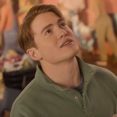 a young man looking up at something in the air while wearing a green polo shirt