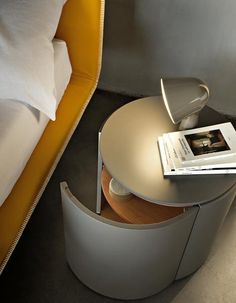 a bed with a magazine on top of it next to a white couch and yellow headboard